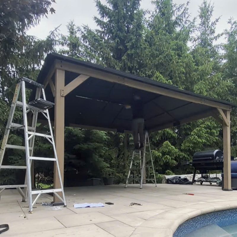 Phil from Bespoke Handyman finishing the roof panels of a hardtop gazebo in an Oakville backyard