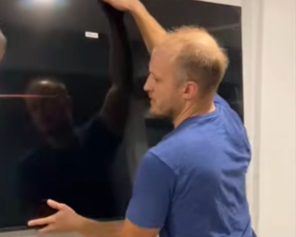 Phil from Bespoke Handyman carefully mounting a large smart television onto a secure wall bracket system in Oakville.