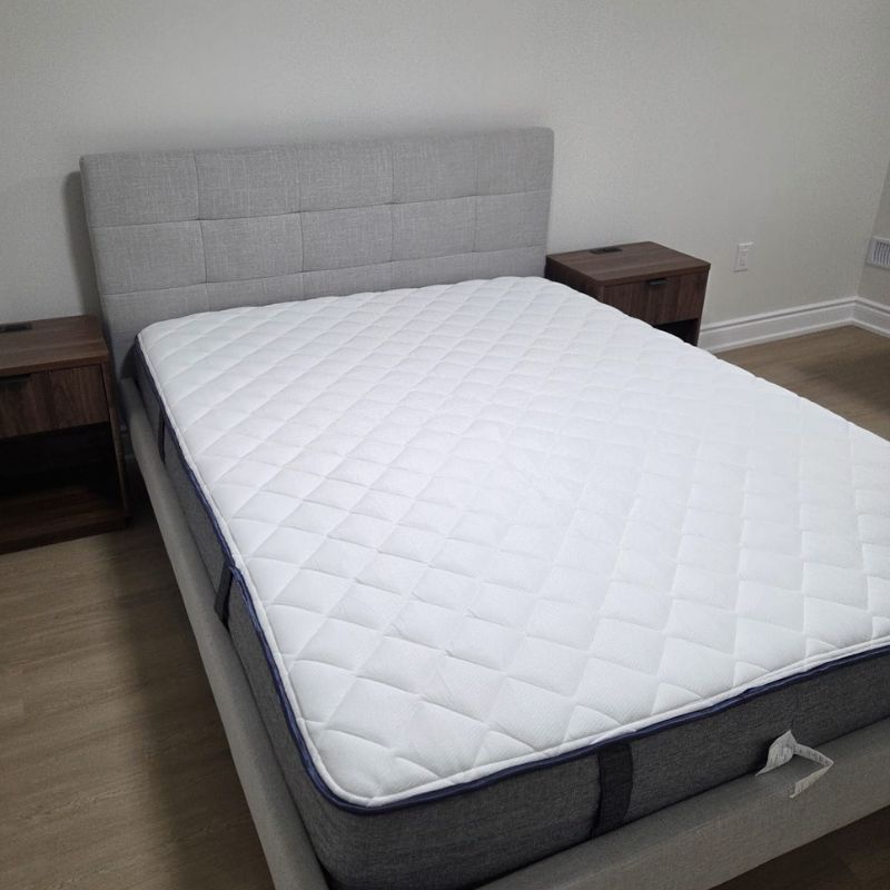 Clean upholstered platform bed frame with tufted headboard assembled for an Oakville master bedroom